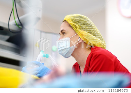 Female anesthesiologist injects anesthesia into patient face mask. General sedation while surgery operation. Paramedic putting oxygen mask for breathing and ventilation of person during resuscitation 112104973