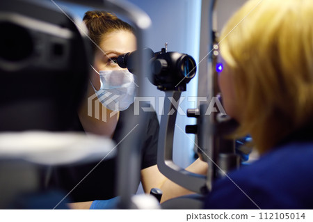 Slit Lamp eye examination with ophthalmologist. Patient during visit by oculist for exam of biomicroscopic analysis of eyelids, sclera, conjunctiva, iris, lens, cornea. Checkup of retina and fundus Slit Lamp eye examination with ophthalmologist. Patient during visit by oculist for exam of biomicroscopic analysis of eyelids, sclera, conjunctiva, iris, lens, cornea. Checkup of retina and fundus 112105014