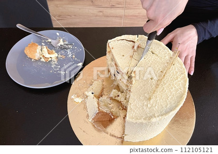 Female hands cut off a piece of festive cake with a knife Female hands cut off a piece of festive cake with a knife 112105121