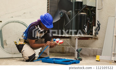 Knowleadgeable engineer unpacking toolkit with professional manometer equipment needed to check freon levels. Certified technician preparing for annual HVAC system maintenance Knowleadgeable engineer unpacking toolkit with professional manometer equipment needed to check freon levels. Certified technician preparing for annual HVAC system maintenance 112105522