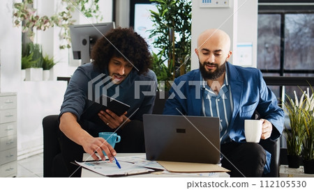 Colleagues comparing data analytics at desk, reviewing marketing information on documents to plan new investment project. Team of workers discussing about development strategy in office. 112105530