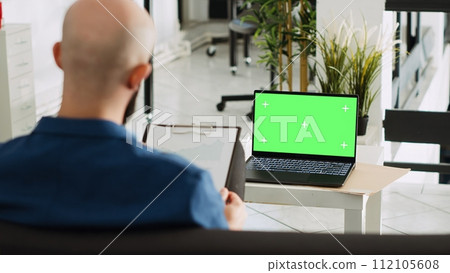 Company worker with greenscreen display reviewing documents, looking at chromakey blank template in open space. Businessman using laptop and analytics for successful research plan. Company worker with greenscreen display reviewing documents, looking at chromakey blank template in open space. Businessman using laptop and analytics for successful research plan. 112105608