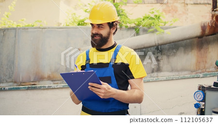 Knowleadgeable engineer doing inspection of freon levels and necessary repairs to prevent major breakdowns. Adept repairman troubleshooting hvac system, writing findings on clipboard 112105637