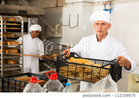 Male baker carrying crate with baked bread Male baker carrying crate with baked bread 112108675