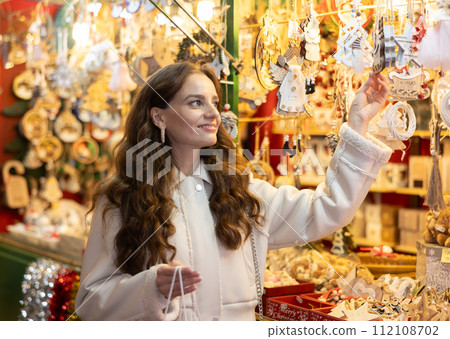 Smiling woman choosing festive home decorations on street Christmas fair 112108702
