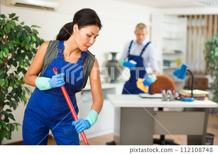 Woman wiping office floor with mop Woman wiping office floor with mop 112108748