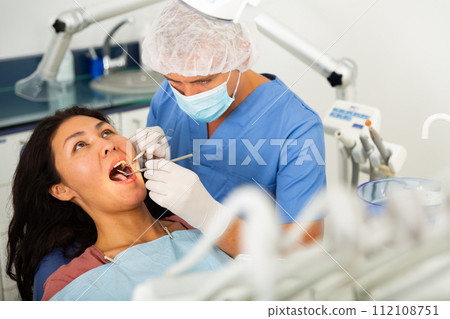 Man dentist examines a female patient with the help of working tools Man dentist examines a female patient with the help of working tools 112108751
