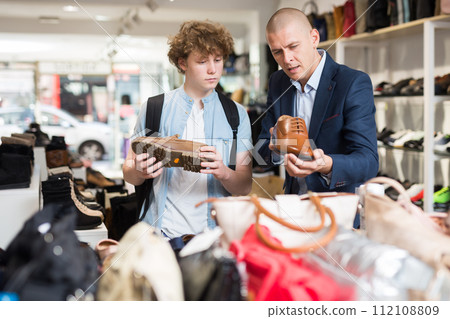 Teenager with shoe store consultant choosing classic shoes 112108809