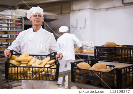 Male baker carrying crate with baked bread Male baker carrying crate with baked bread 112109277