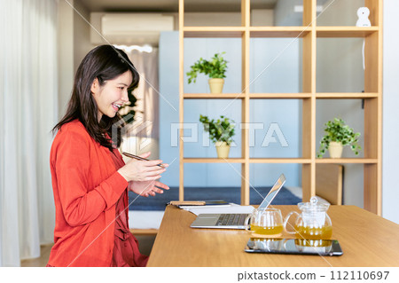 一名 30 多歲的女性使用筆記型電腦在家進行遠距辦公 112110697