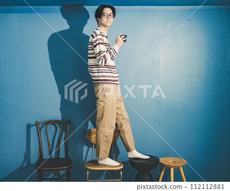 年輕人站在藍色背景的椅子上工作 112112881