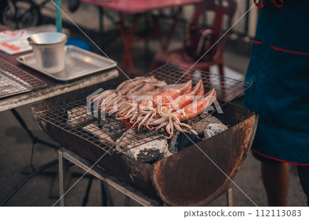 Squid grilled on a grill at a street market Squid grilled on a grill at a street market 112113083