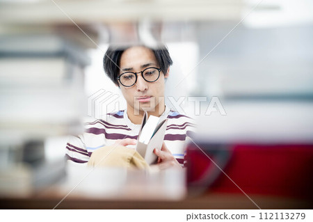 一個年輕人在大量書籍的包圍下讀書 112113279