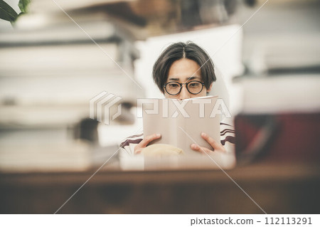 一個年輕人在大量書籍的包圍下讀書 112113291