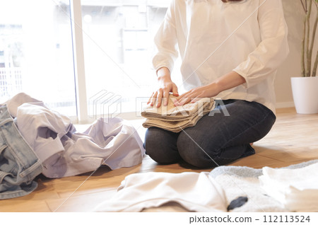 young woman putting away laundry young woman putting away laundry 112113524