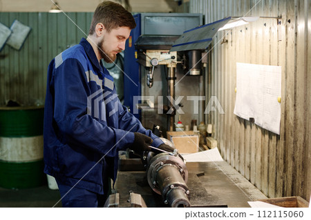 Medium side view shot of young man doing metalwork in factory workshop, copy space Medium side view shot of young man doing metalwork in factory workshop, copy space 112115060