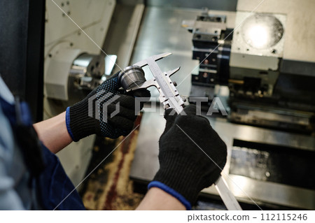 High angle view closeup of hands of unrecognizable turner measuring size of metal part High angle view closeup of hands of unrecognizable turner measuring size of metal part 112115246