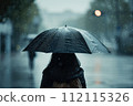 Back view of woman walking in the street with black umbrella on a rainy day. 112115326