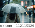 Back view of woman walking in the street with transparent umbrella on a rainy day. 112115329