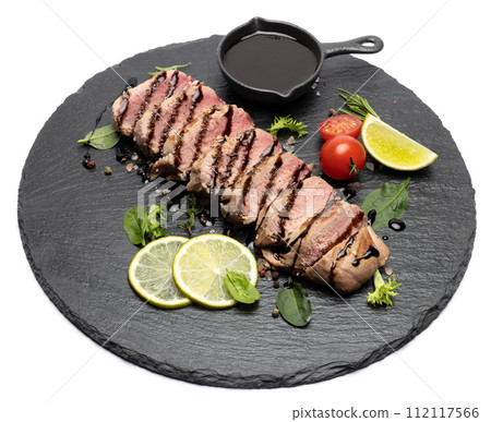 sliced grilled cooked piece of tuna fillet on black stone serving board sliced grilled cooked piece of tuna fillet on black stone serving board 112117566
