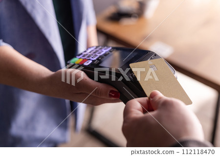 NFC credit card payment. Woman paying with contactless credit card with NFC technology. Wireless money transaction. Card machine in male hand on sunlight background 112118470