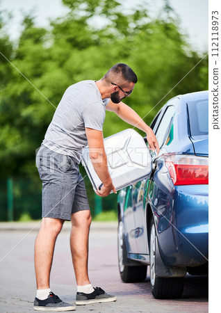 Forced stop because of ran out of fuel. Skilled driver refueling car gas tank with gasoline from canister he picked for unforeseen circumstances. Forced stop because of ran out of fuel. Skilled driver refueling car gas tank with gasoline from canister he picked for unforeseen circumstances. 112118973