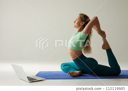 girl doing morning exercises and stretching online on a white background, online fitness training 112119985