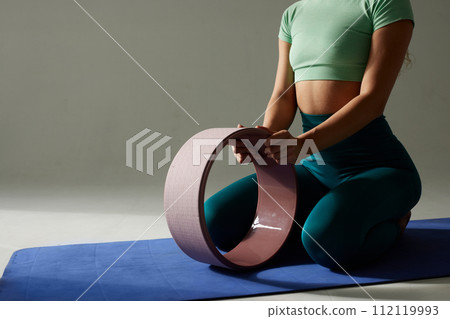 young flexible girl doing gymnastics, flexibility and stretching using a yoga wheel online on a white background young flexible girl doing gymnastics, flexibility and stretching using a yoga wheel online on a white background 112119993