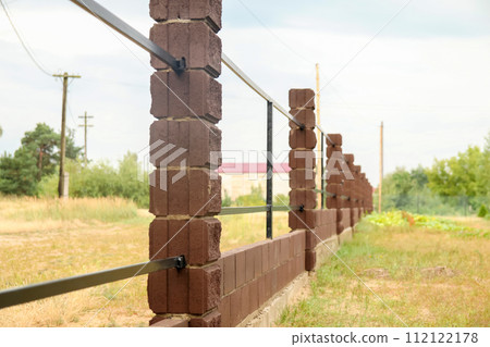 Brown metal profile fence with block posts. Incline construction Brown metal profile fence with block posts. Incline construction 112122178