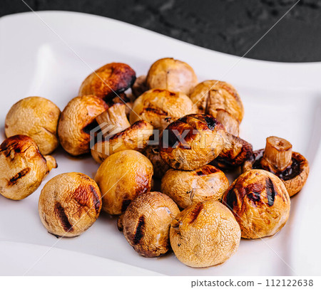 Baked mushrooms in plate on a stone table 112122638