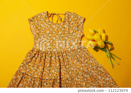 Summer dress and flowers on yellow background, top view 112123074