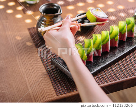 girl eating sushi rolls wrapped with tuna and avocado girl eating sushi rolls wrapped with tuna and avocado 112123266