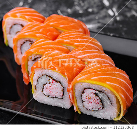 sushi rolls with salmon and crab on black plate 112123368