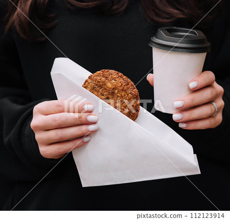 Woman holding a mug of coffee and Oatmeal Cookies in her hands in coffee shop Woman holding a mug of coffee and Oatmeal Cookies in her hands in coffee shop 112123914