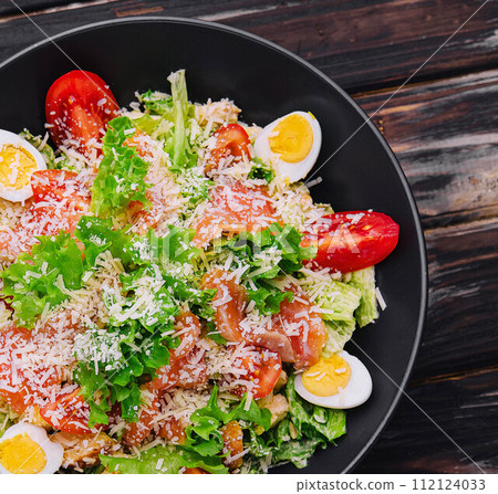 Salad with salmon, lettuce, boiled eggs, cherry tomatoes and parmesan cheese Salad with salmon, lettuce, boiled eggs, cherry tomatoes and parmesan cheese 112124033