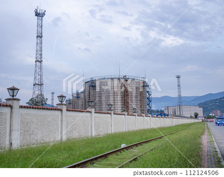 Large fuel tanks. Tanks and ladders of the tank farm. The gloomy atmosphere of an industrial area. 112124506