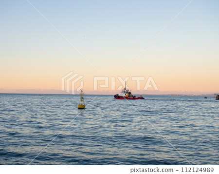 Port area. Tugboat on the road. A buoy in the bay of the port. Marine urban landscape. Port area. Tugboat on the road. A buoy in the bay of the port. Marine urban landscape. 112124989