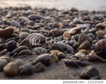 Pebbles on the seashore close-up. Rocky beach. Stones close-up with bokeh. Gray natural background.   Waves and wet pebbles 112125243