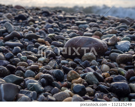 Pebbles on the seashore close-up. Rocky beach. Stones close-up with bokeh. Gray natural background. The concept of rest on the seashore. The Velvet season.   Waves and wet pebbles 112125249