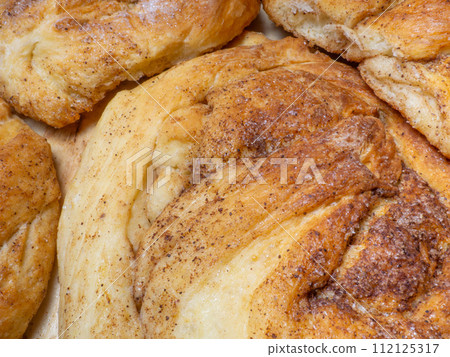 Wicker bun with cinnamon and sugar. Bread product of an unusual shape. Homemade baking. Buns with a ruddy crust. 112125317