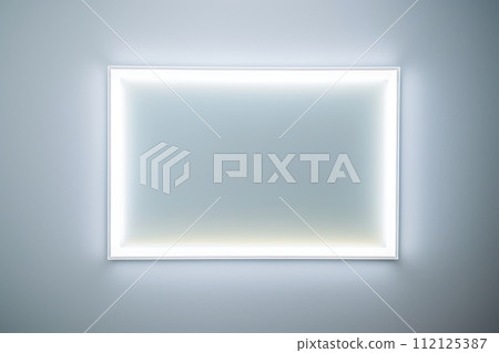 A glowing white rectangle frame on a wall in a minimalist white room 112125387