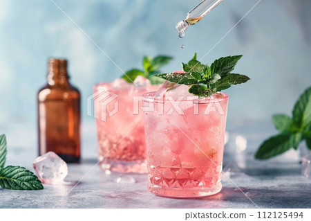 Two glasses filled with crushed ice and a blush beverage, garnished with mint leaves. Cannabis cocktail 112125494