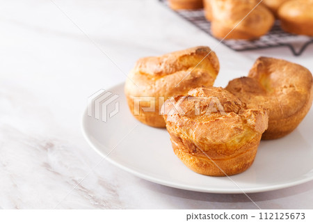 Popovers or Yorkshire pudding on a white plate on a white background, appetizer, breakfast, copy space 112125673