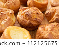 A lot of fresh hot popovers on wood plate or wooden board. Easy cooking, tasty breakfast, close up. Yorkshire pudding 112125675
