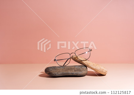 Vision glasses with black frames on stones against a pink background Vision glasses with black frames on stones against a pink background 112125817