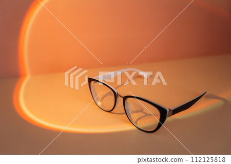 Vision glasses with black frames under orange light Vision glasses with black frames under orange light 112125818