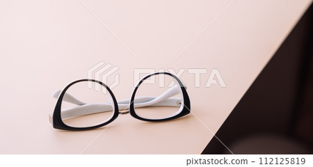 Folded vision glasses with black frames on a light surface Folded vision glasses with black frames on a light surface 112125819