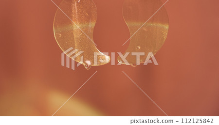 Transparent eye patches with serum hanging against a red background 112125842