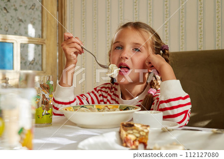 Child eats dumplings sitting at the table at home Child eats dumplings sitting at the table at home 112127080