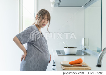 Pregnant woman in late pregnancy suffering from back pain in the kitchen Pregnant woman in late pregnancy suffering from back pain in the kitchen 112127285